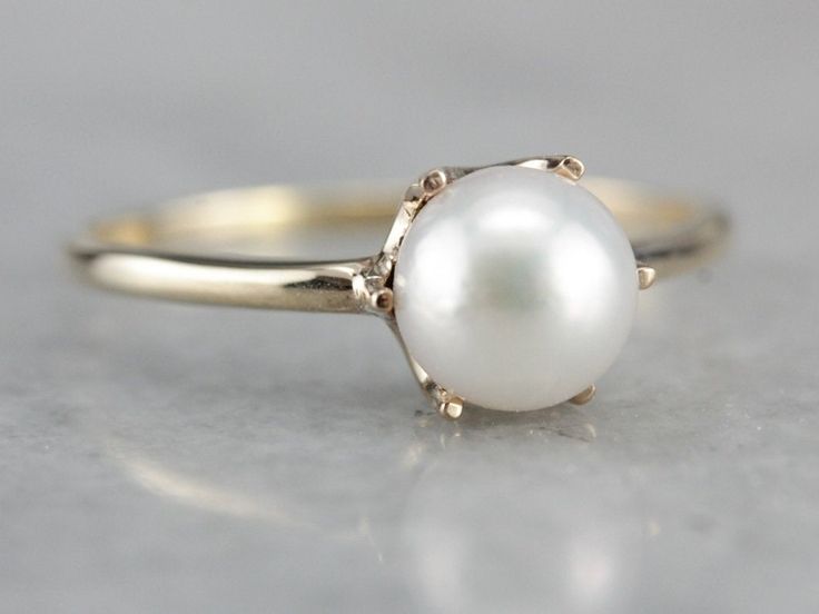 "Perfect for stacking or even to wear alone, this minimalist pearl ring is as simple as can be. Crafted of yellow gold, six prongs hold a shining pearl. Metal: 10K/14K Yellow Gold Gem: Pearl Gem Measurements: 6.7 mm, Round Ring Size: 7.75 Marks: \"10K 14K\" Stamped on the inside band SKU #: MTR5PM7R Each piece has been identified and graded by a Graduate Gemologist who has been certified by the Gemological Institute of America (GIA). We have four brick and mortar storefronts in Maine, Massachuse White Solitaire Pearl Ring, White Solitaire Pearl Ring, Round Cut, Classic White Gold Pearl Ring With Prong Setting, Classic White Gold Akoya Pearl Ring, Classic White Akoya Pearl Ring, Classic White Pearl Ring, White Akoya Pearl Timeless Ring, White Timeless Round Cut Pearl Ring, Timeless White Round Cut Pearl Ring