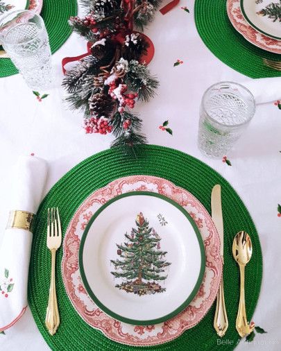 a christmas table setting with plates, silverware and napkins on top of green place mats