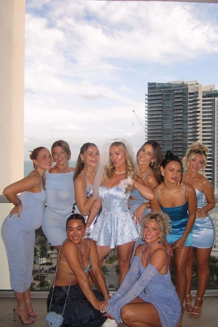 a group of women standing next to each other on top of a roof in front of tall buildings