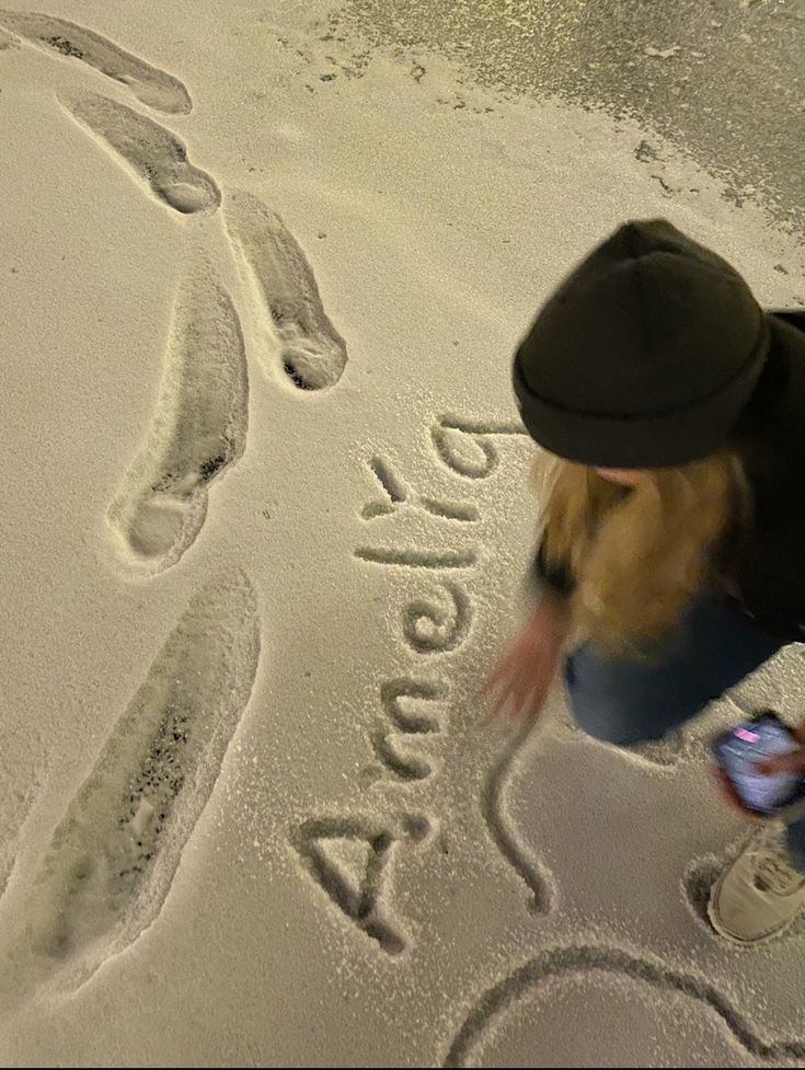 a person writing on the sand with their feet and handwritten name in the sand