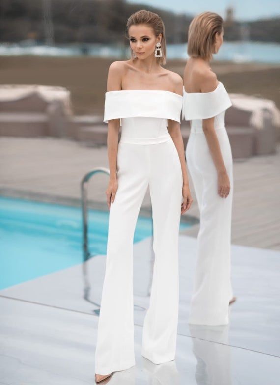 two women standing next to each other in front of a swimming pool wearing white outfits