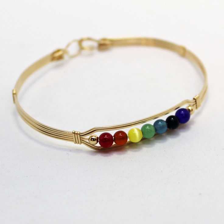 "A contemporary little bracelet of five strands of 14kt gold filled wire with a center design featuring the seven colors of the chakra in 4mm beads, accented with two smaller gold beads. Perfect for the girl who loves to get her \"metaphysical\" on! Stackable, too, along with many of my other wirewrapped bracelets! The sturdy built-in hook and eye clasp is easy to get on and off by yourself. Choose the size you need for a comfortable custom fit." Gold Hand-wrapped Bracelets For Gifts, Hand Wrapped Gold Bracelets As Gift, Hand Wrapped Gold Bracelets For Gift, Adjustable Gold Spiritual Wrap Bracelet, Minimalist Gold Beaded Bracelets Hand Wrapped, Gold Spiritual Hand Wrapped Bracelets, Adjustable 14k Gold-filled Jubilee Bracelet, Gold Hand Wrapped Beaded Bangle Bracelets, Spiritual Hand Wrapped Gold Bracelets