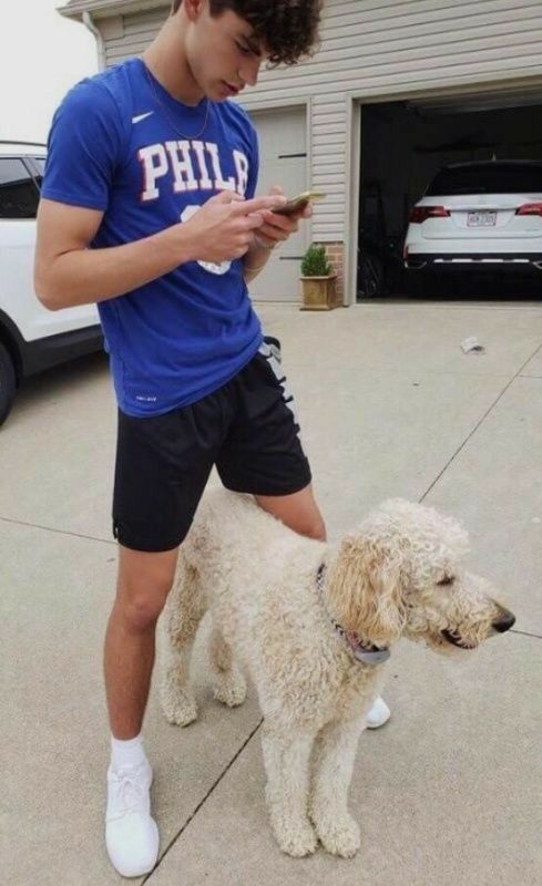 a young man standing next to a white dog