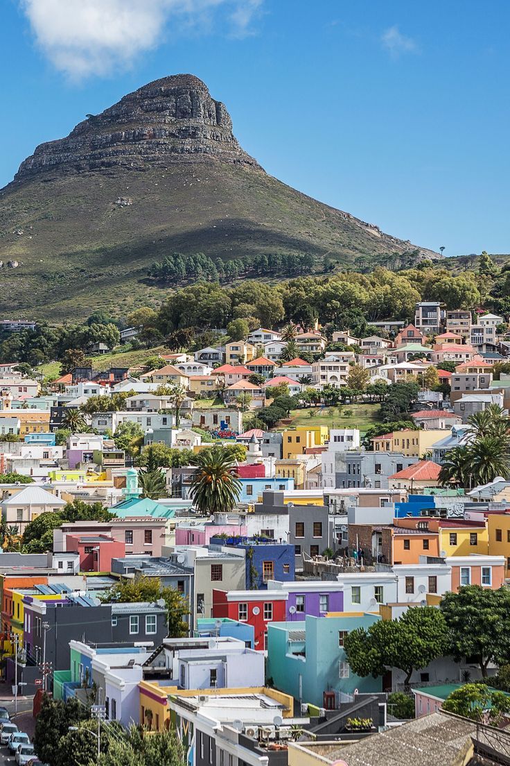 the city has many colorful houses on it's sides and there is a mountain in the background