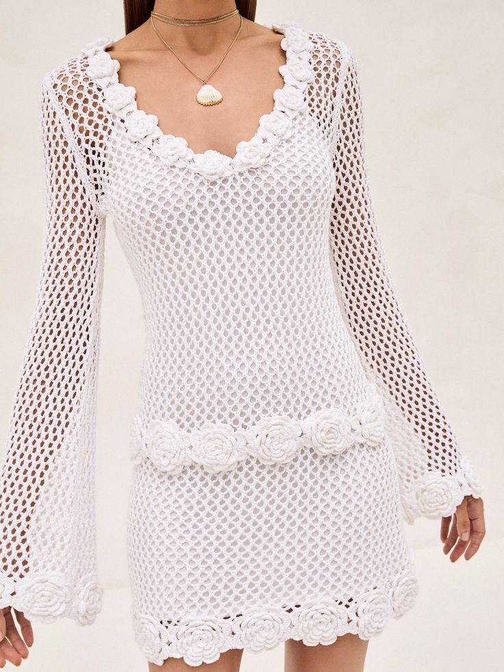 a woman wearing a white crochet dress