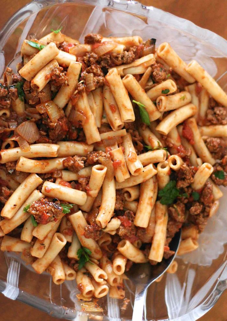 a bowl filled with pasta and meat on top of a wooden table