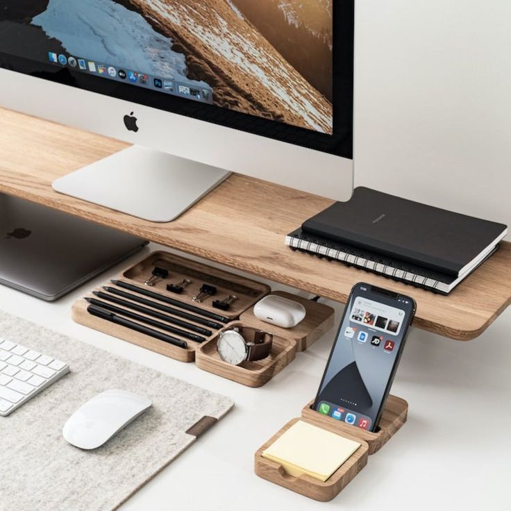 an apple computer, keyboard, mouse and cell phone are sitting on a wooden desk