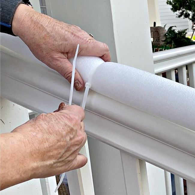 an older person is holding a roll of white tape on the outside of a house