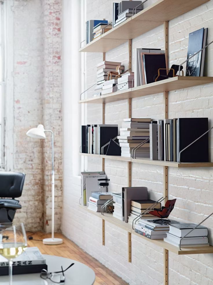 a living room filled with lots of furniture and bookshelves on top of a white brick wall