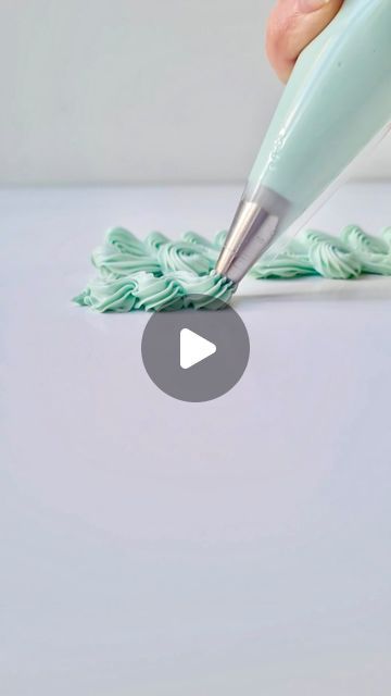 a person is using a pen to write something on the table with green icing