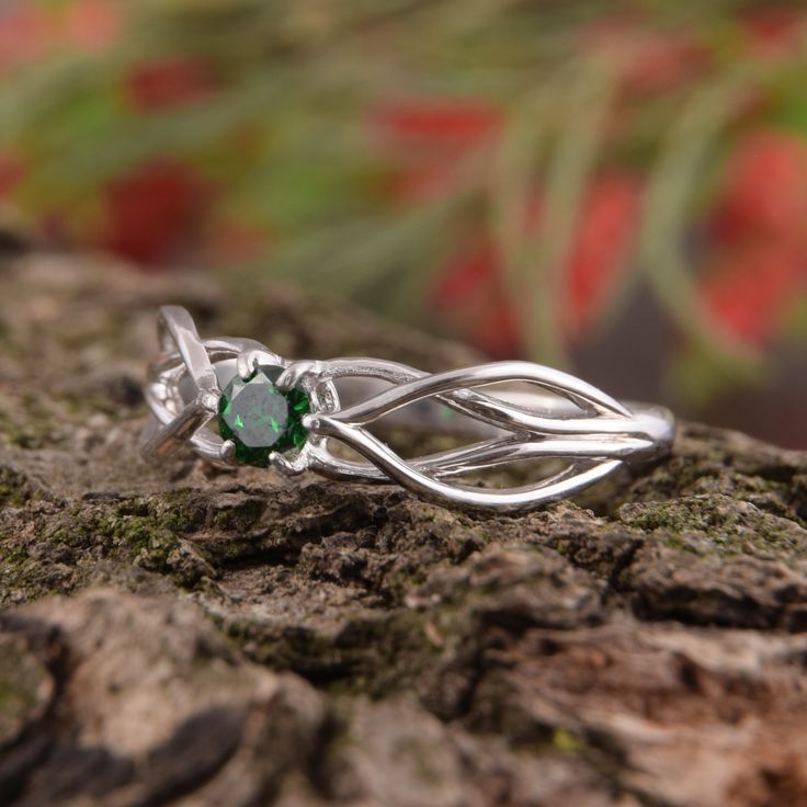 a close up view of a ring with leaves on the top and green stone in the middle