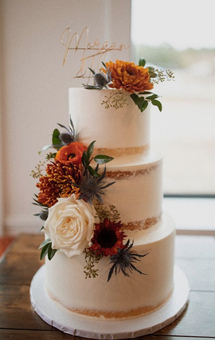 a three tiered wedding cake with flowers on top