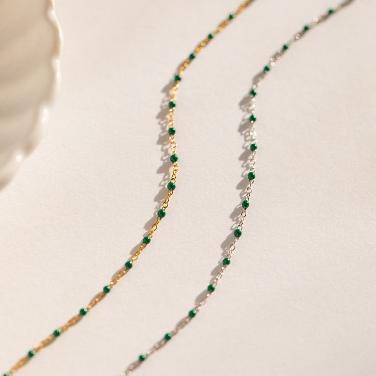 This beaded boho necklace is made of soft dainty, glistening emerald green beads that dance along your collarbone. It pairs wonderfully with a simple white blouse, but also goes well with a fancier dress for an evening out! Stunning and stylish, this beautiful beaded charm necklace adds a fun, flirty touch to any outfit. Material: High Quality Solid 925 Sterling Silver. Finish: Sterling Silver ∙ 18K Gold Featuring a dainty Beaded Necklace with ~2mm Emerald Green Beads spaced ~5mm apart, with adj Dainty Green Beaded Necklaces With Round Beads, Dainty Green Beaded Necklace With Round Beads, Green Beaded Chain Choker As Gift, Elegant Green Beaded Necklaces With Polished Beads, Dainty Green Beaded Necklaces, Elegant Green Beaded Necklace With Round Beads, Elegant Beaded Emerald Necklaces, Delicate Chain Beaded Necklaces For Party, Elegant Beaded Emerald Necklace