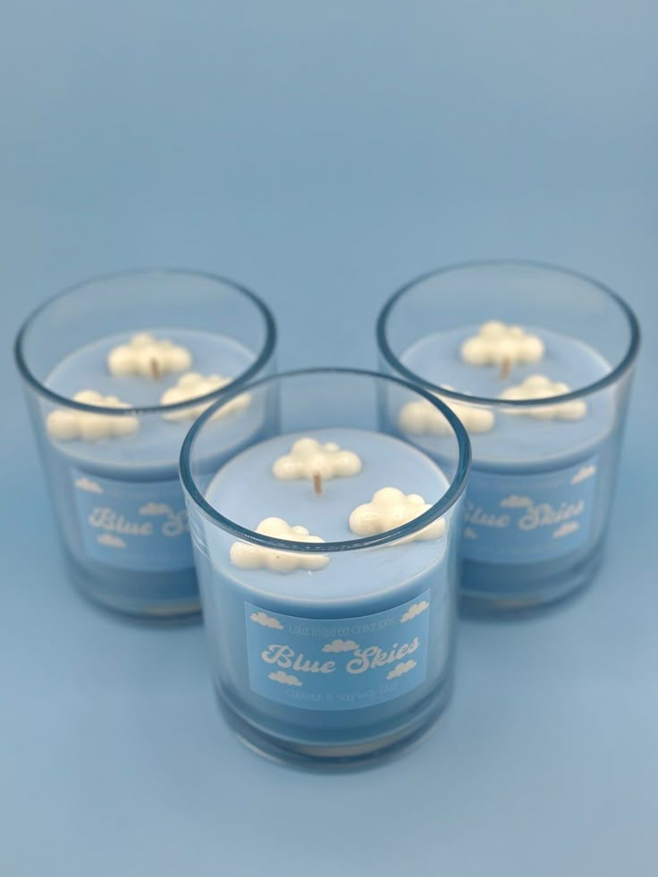 three blue glass candles with small white flowers on the top and one candle in the middle