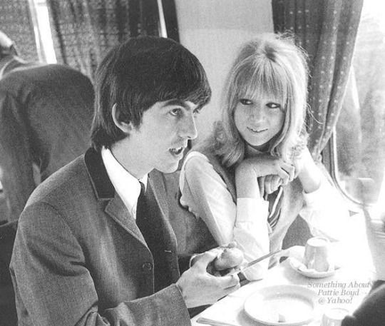 a man and woman sitting at a table in front of each other with plates on it