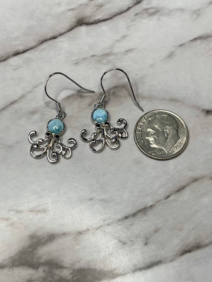 Oh these are the cutest little octopus earrings. The body is a beautiful Larimar round and bezel set. Fun little legs and navy blue enameled eyes. These are handmade by me or my partner in our shop on the island of Kauai in Hawaii. We have been making handmade jewelry for over 20 years. We would love to see you come and visit us but we are just as happy for you to shop a little piece of paradise here on Etsy. Mahalo Light Blue Ocean-inspired Jewelry For Gift, Ocean-inspired Light Blue Jewelry For Gift, Light Blue Ocean-inspired Jewelry Gift, Whimsical Blue Round Jewelry, Whimsical Round Blue Jewelry, Ocean-inspired Blue Earrings For Gifts, Whimsical Jewelry With Matching Round Earrings, Cute Hypoallergenic Turquoise Jewelry, Whimsical Round Jewelry With Matching Earrings