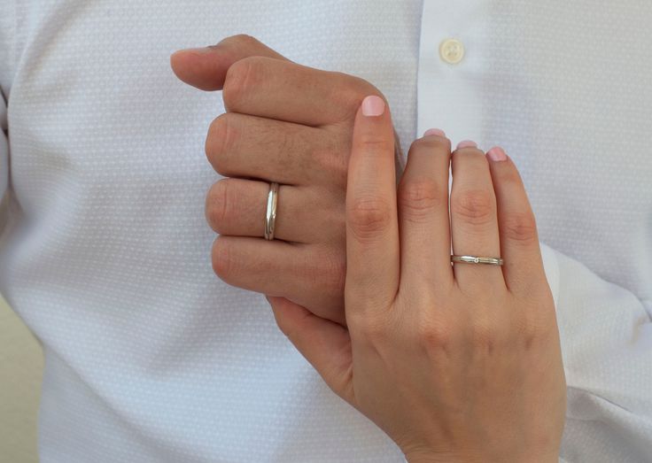 a man and woman holding hands with wedding rings on their fingers in front of them