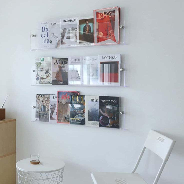 several magazines are hanging on the wall above a white table and chair in a room