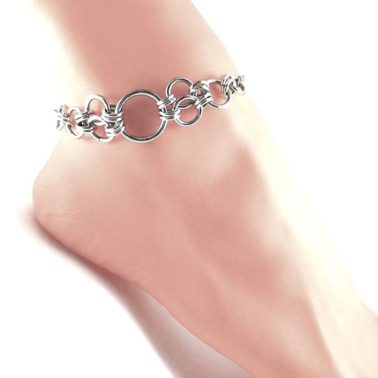 a woman's foot wearing a silver chain ankle bracelet with circles on the side