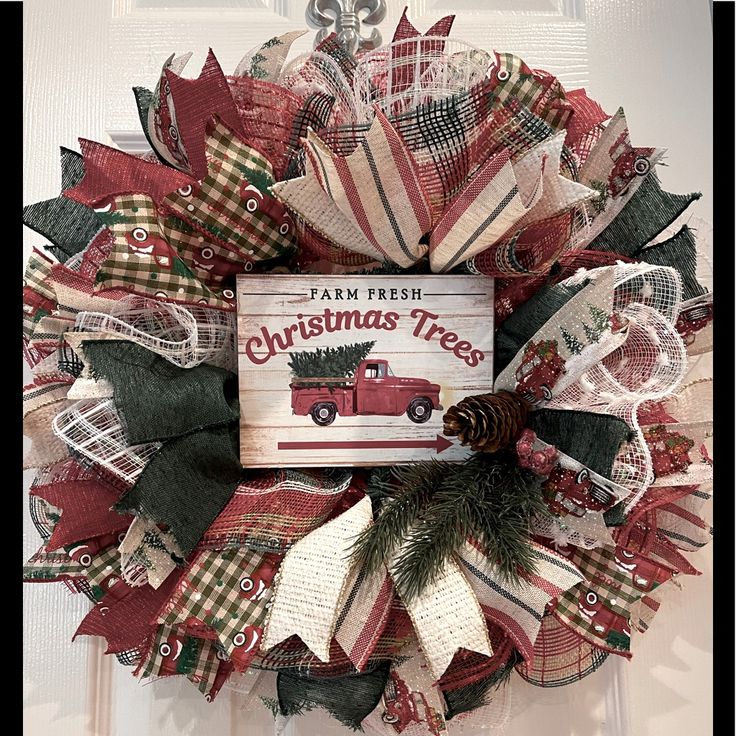 a christmas wreath is hanging on the front door with a book about christmas trees in it