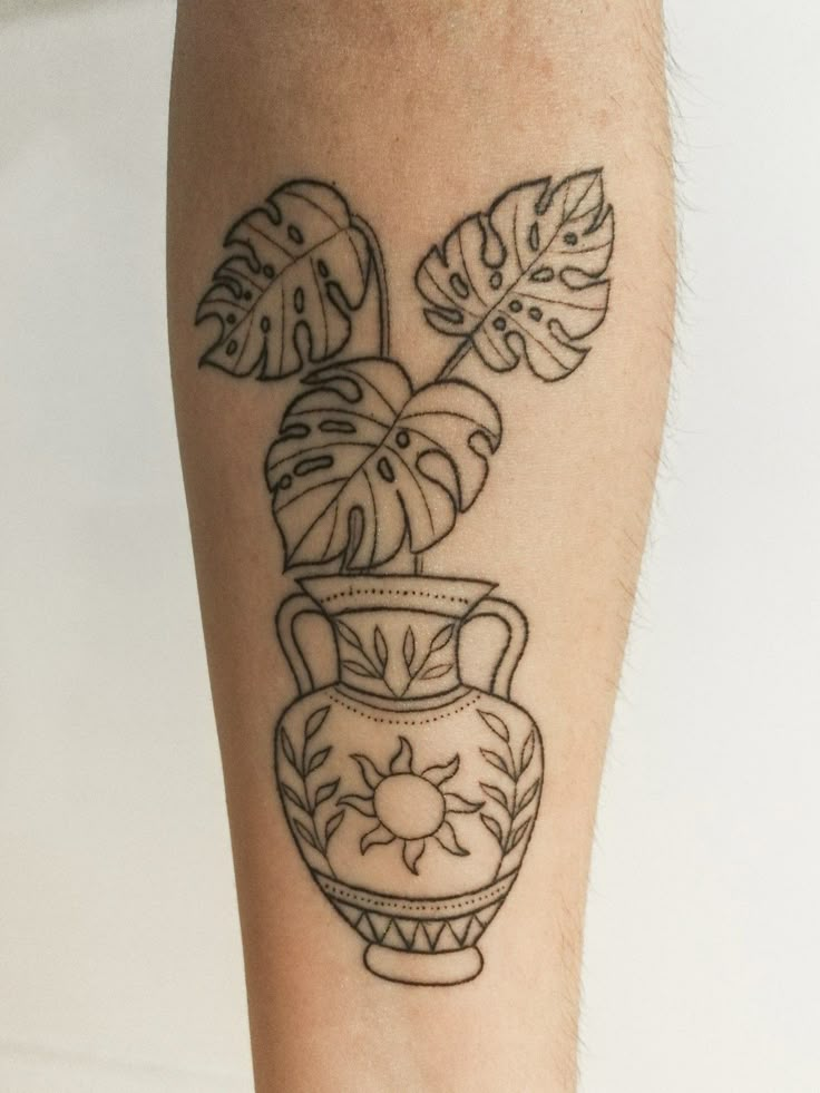 a tattoo on the leg of a person with a potted plant and leaves in it