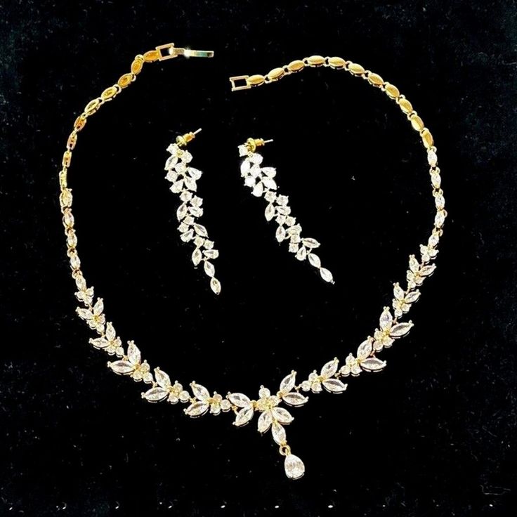 a gold necklace and earring set with white flowers on black velvet background, circa 1950's