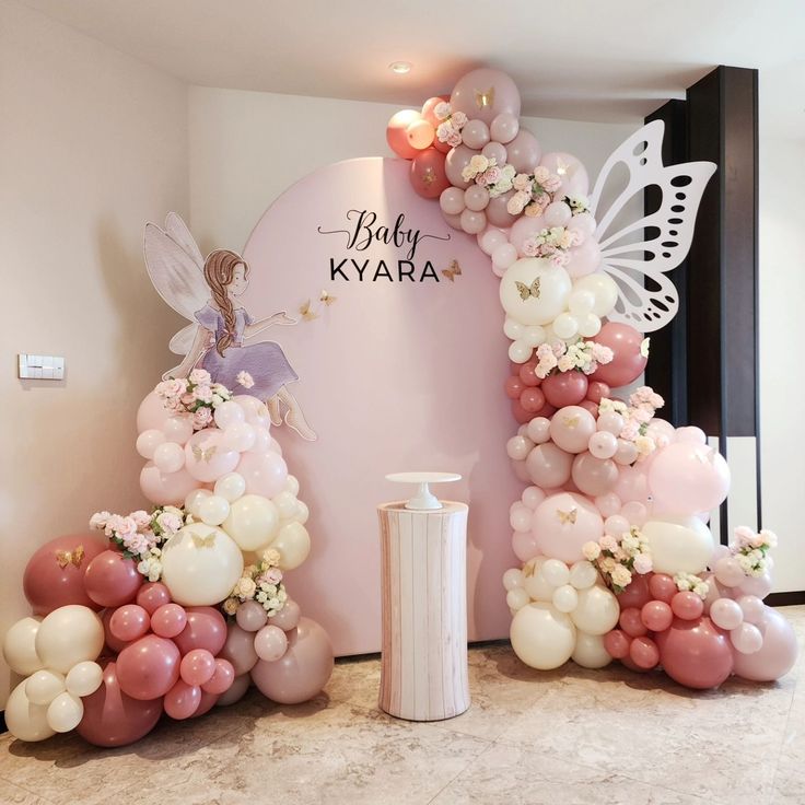 balloons are arranged in the shape of an arch with fairy characters on it and flowers