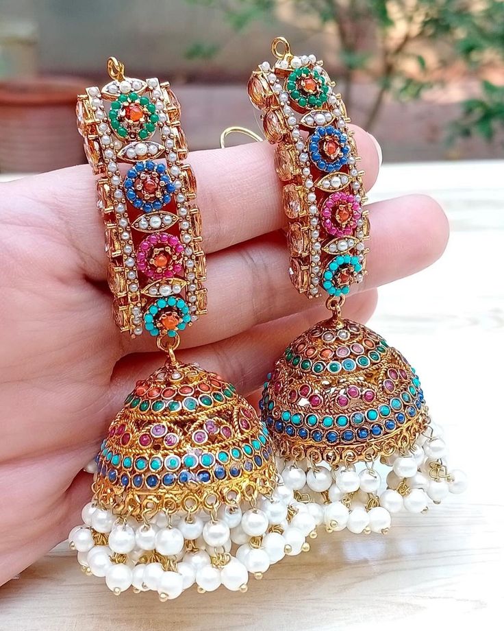 a person holding some kind of earrings in their hand and it is decorated with colorful beads