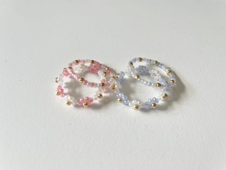 three beaded rings sitting on top of a white surface