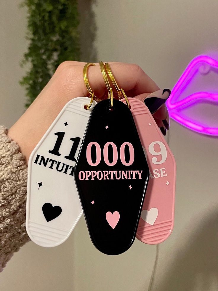 a person holding three different colored tags in their left hand, one is pink and the other is black