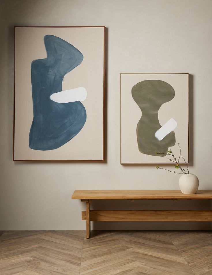 two paintings hang on the wall next to a table with a vase and plant in it