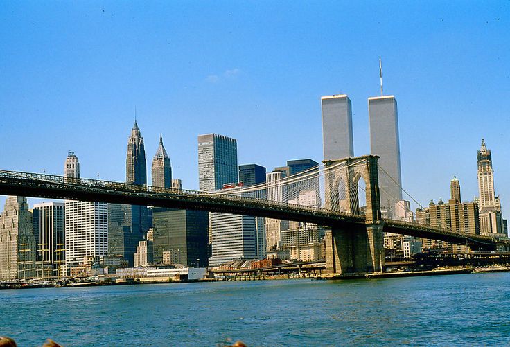 the city skyline is seen from across the water in front of a bridge and skyscrapers