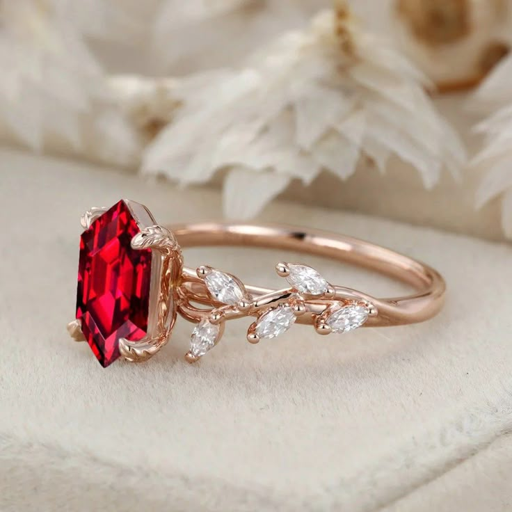 a close up of a ring with a red stone in the center and leaves on it