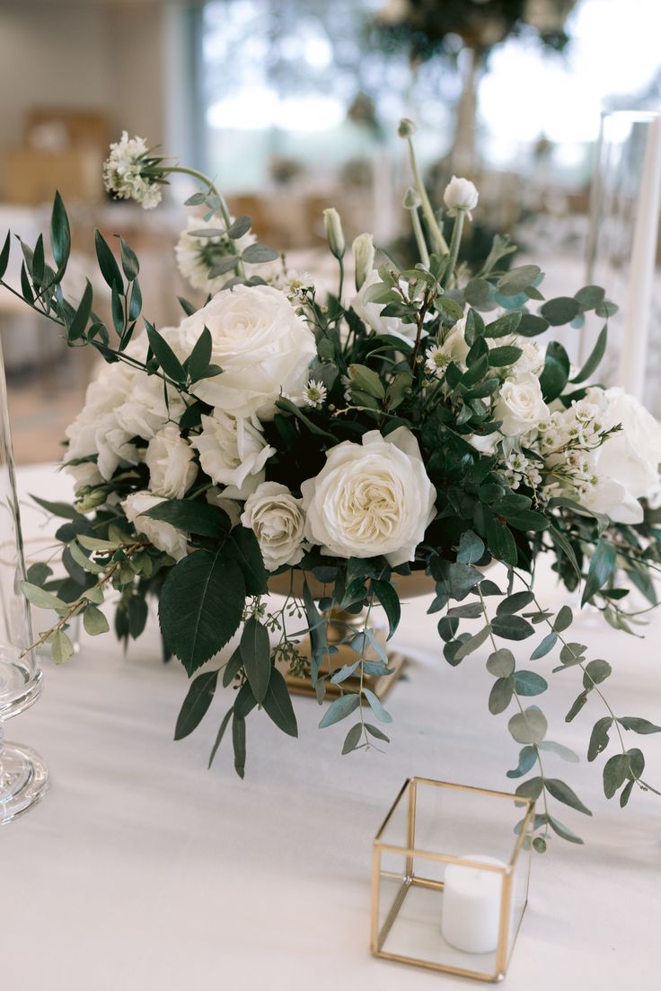 a vase filled with white flowers sitting on top of a table next to a candle holder