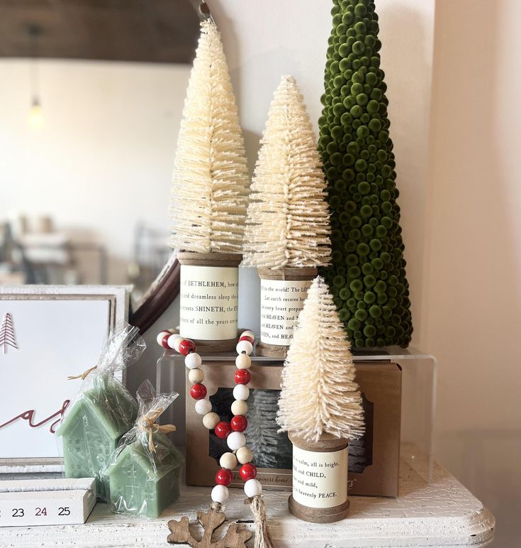 christmas trees are displayed on a mantle in front of other ornaments and decorating items