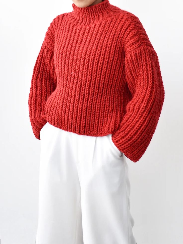 a woman wearing a red sweater and white pants