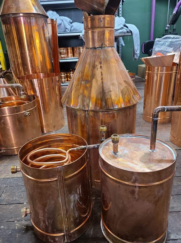 several copper colored pots are sitting on the ground