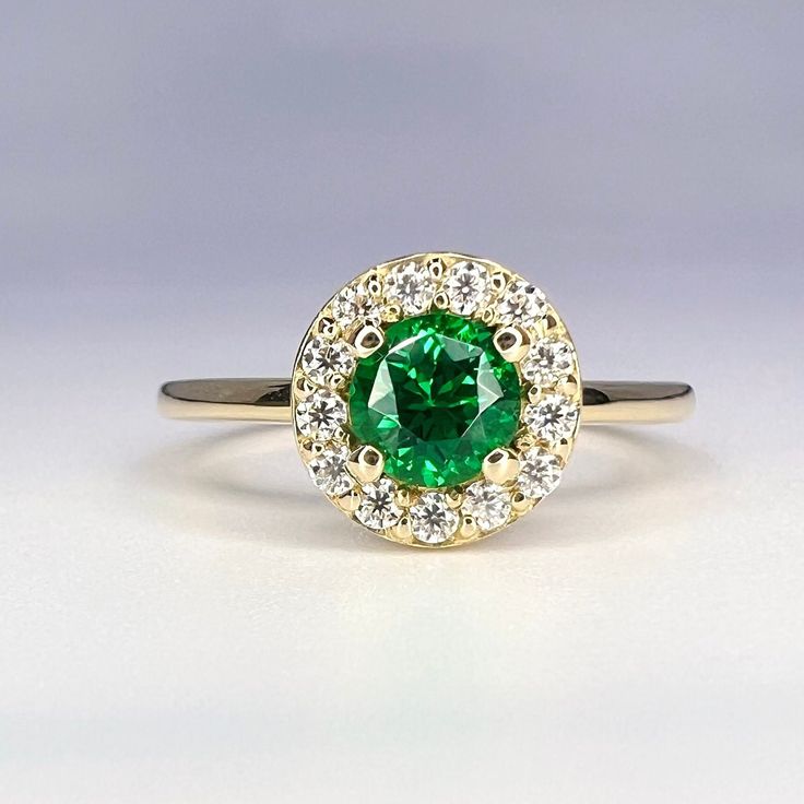 a green and white diamond ring sitting on top of a gray surface with diamonds around it