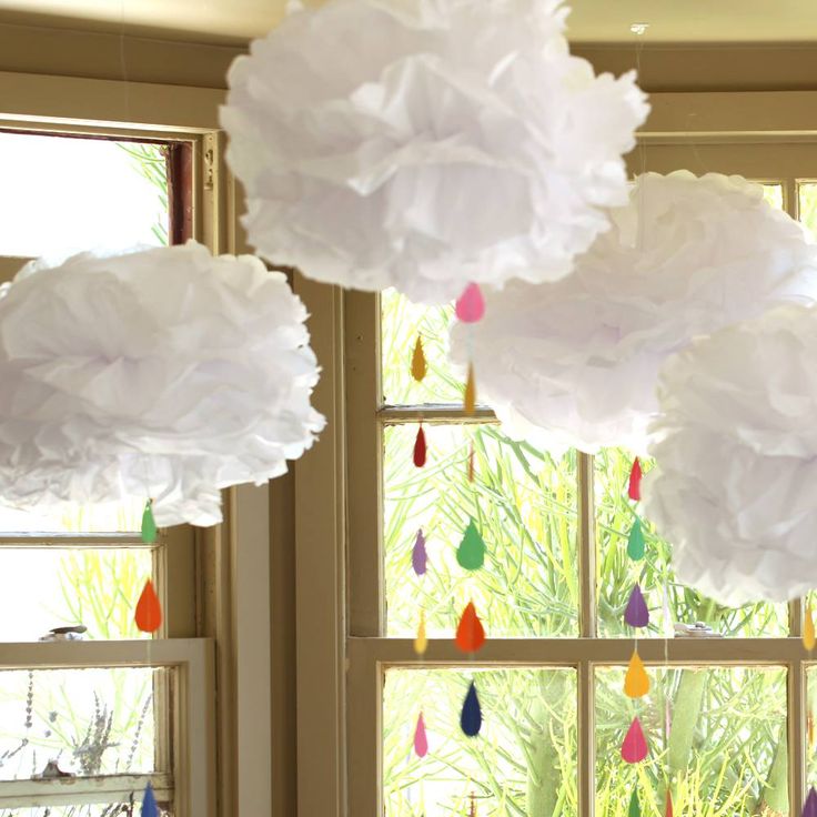 paper flowers hanging from the ceiling in front of a window