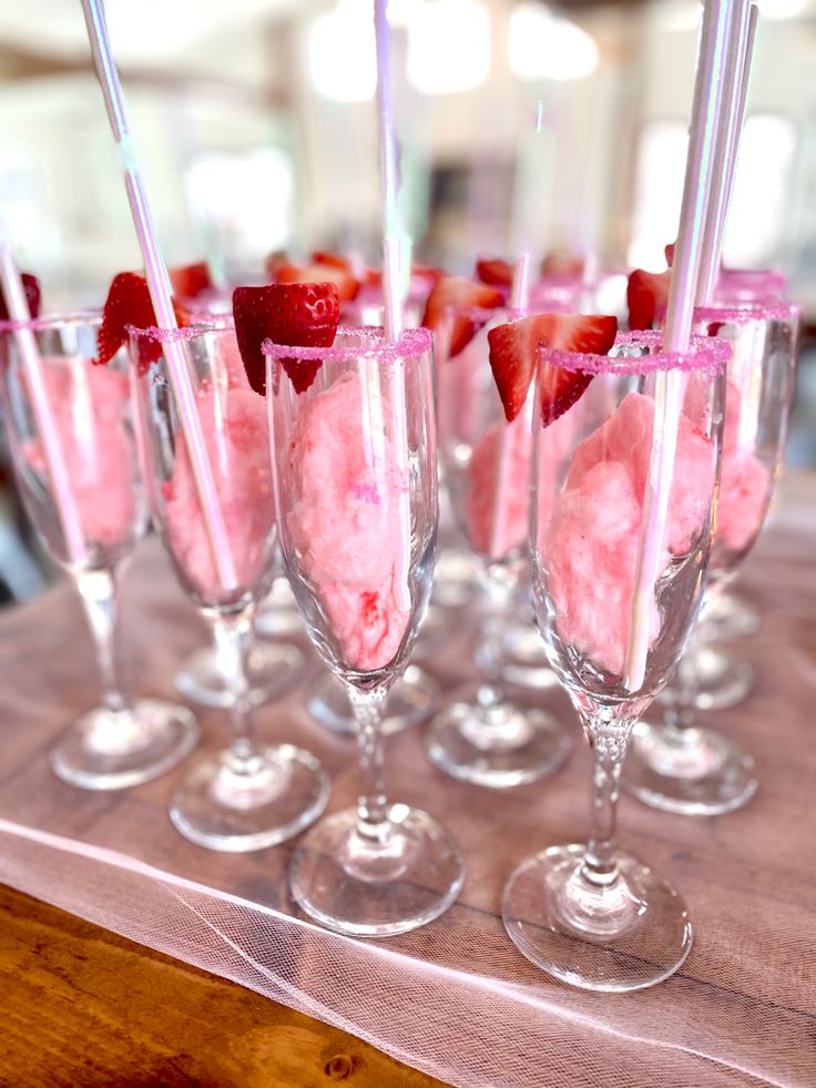 several glasses filled with ice cream and strawberries on top of a wooden table next to each other