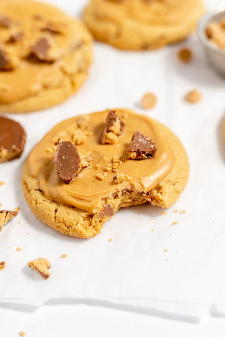 chocolate chip cookies with peanut butter frosting on parchment paper