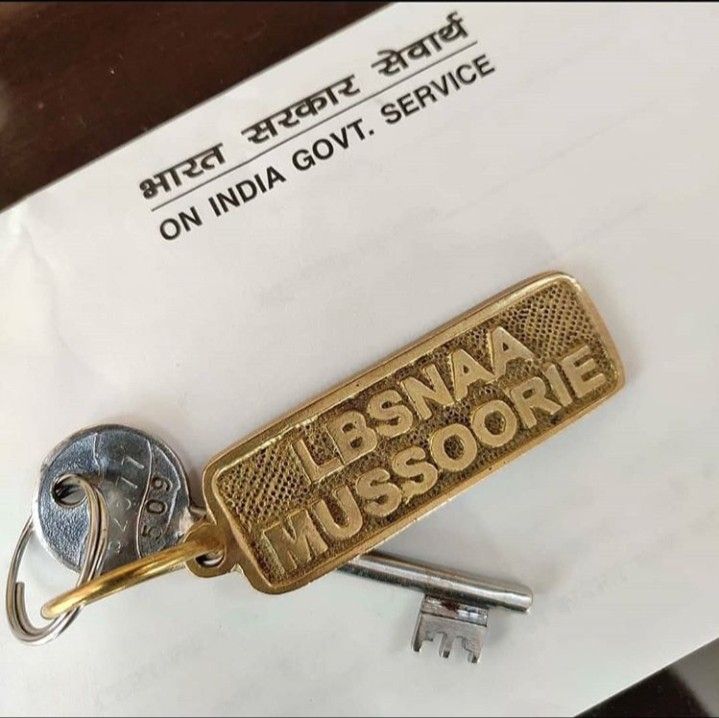 a keychain with the words bsna mussorie written in gold on it