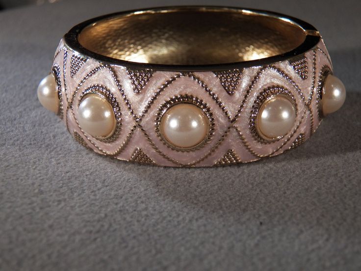 I am offering you this lovely vintage yellow gold tone fancy WIDE bangle bracelet. It features incredible art deco style of work, all with a very uniform etched raised designs on the entire top surface of this very high end spectacular bangle bracelet , with fabulous cream / ivory colored enameling. There are 10 total large round shaped domed faux pearls. It has a very appealing design and It measures app. 2.25 inches in diameter. measures app. 1 inch wide. This is hinged , so it should fit just Pearl Bangle Bracelet, Incredible Art, Pearl Bangle, Enamel Bangle, Brooch Jewelry, Genuine Turquoise, Favorite Rings, Art Deco Style, Vintage Yellow