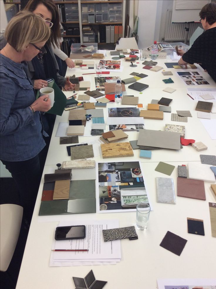 two women standing at a table covered in samples of different colors and sizes of tiles