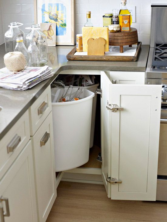 a kitchen with an open trash can in the middle of the cabinet and other items on the counter