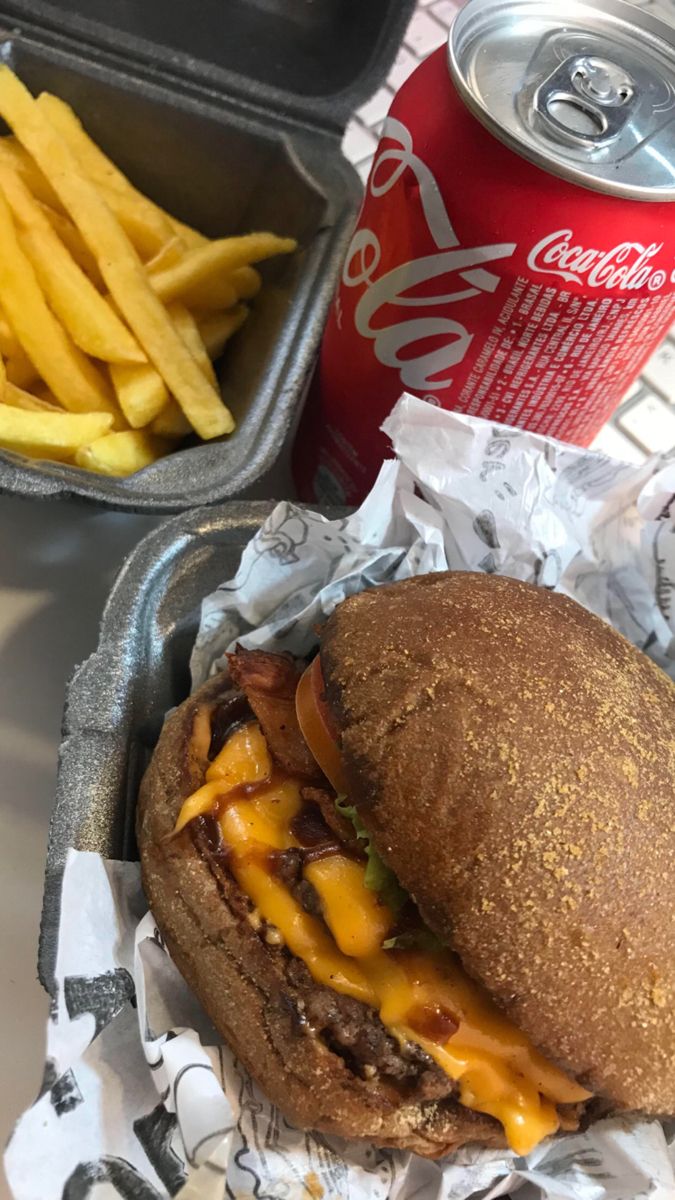 a hamburger and french fries are sitting on a table next to a can of soda