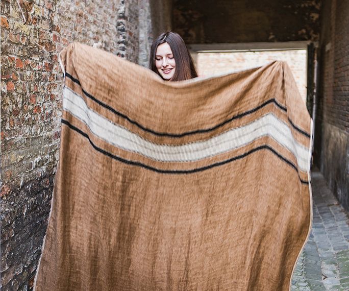 a woman holding up a blanket in an alley way