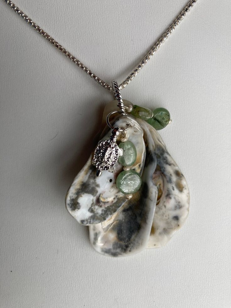 "Natural sea shell pendant necklace, ocean shells clustered with a Sterling Turtle ( plated ) charm and Kyanite charms on Sterling plated rings. Unique seashell pendant measures 2 1/4\" X 1 1/4''. Comes with a Sterling plated 20\" loop chain. Makes a great summer choker necklace.  Sterling silver necklace is not included, it was used as DISPLAY ONLY.  But it can be purchased for $52.50 and necklace 20'' and  is stamped 925 Italy. You can compare the size of the shells to the $0.50 cent piece in the pictures. All my necklaces are different and would be considered one of a kind. View my collection of Kingman Arizona Turquoise here: https://www.etsy.com/shop/MoonwaterJewelryShop?section_id=28192591  I've been selling on eBay since 2003 Came to Etsy to sell jewelry. Returns and exchange detail Silver Dangle Charm Necklace With Natural Stones, Shell Pendant Jewelry With Pearl Charm, Shell Pendant Charm Necklaces For Gifts, Ocean-inspired Silver Necklaces With Charms, Shell Charms Jewelry, Silver Shell Jewelry With Pearl Charm, Silver Dangle Jewelry With Shell, Pearl Charm Pendant Shell As Gift, Shell Necklace With Large Pendant