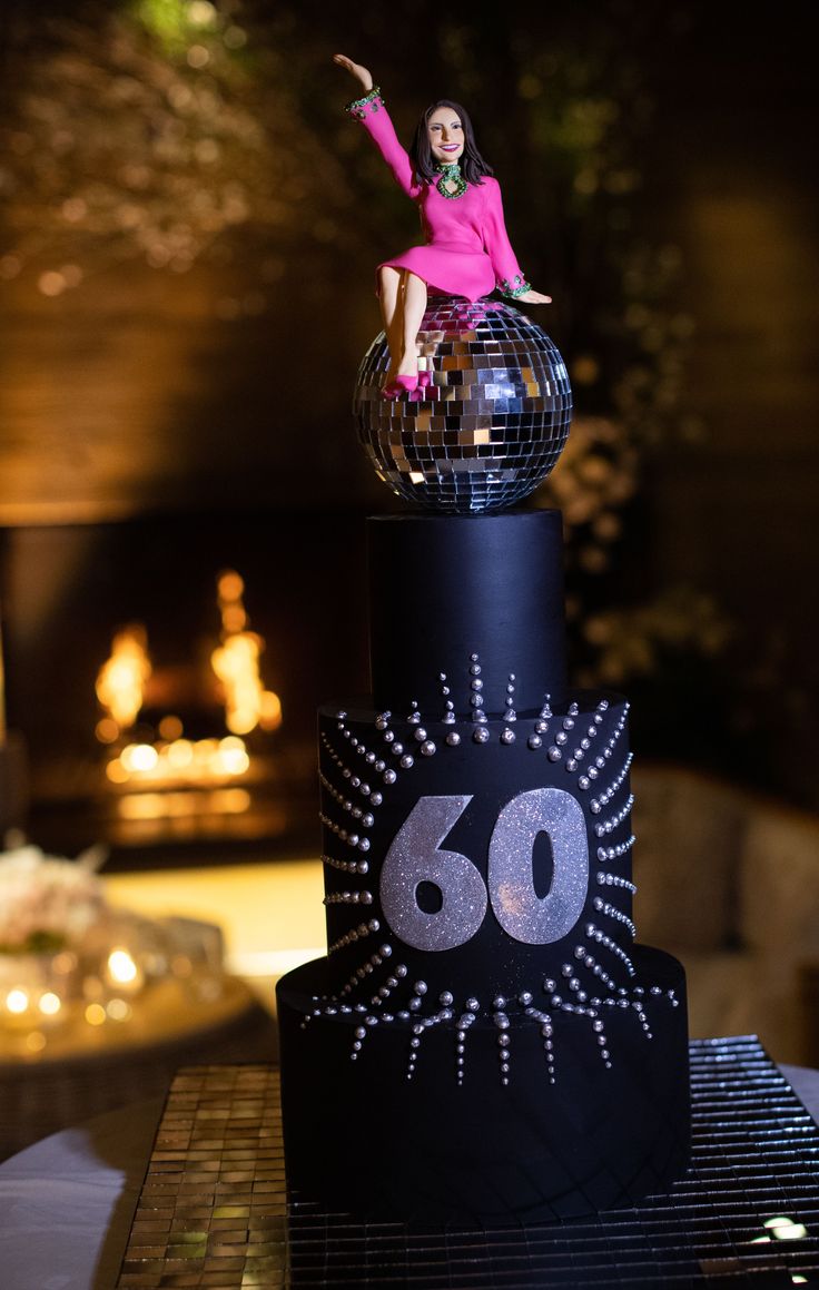 a woman in a pink dress is on top of a black and silver disco ball