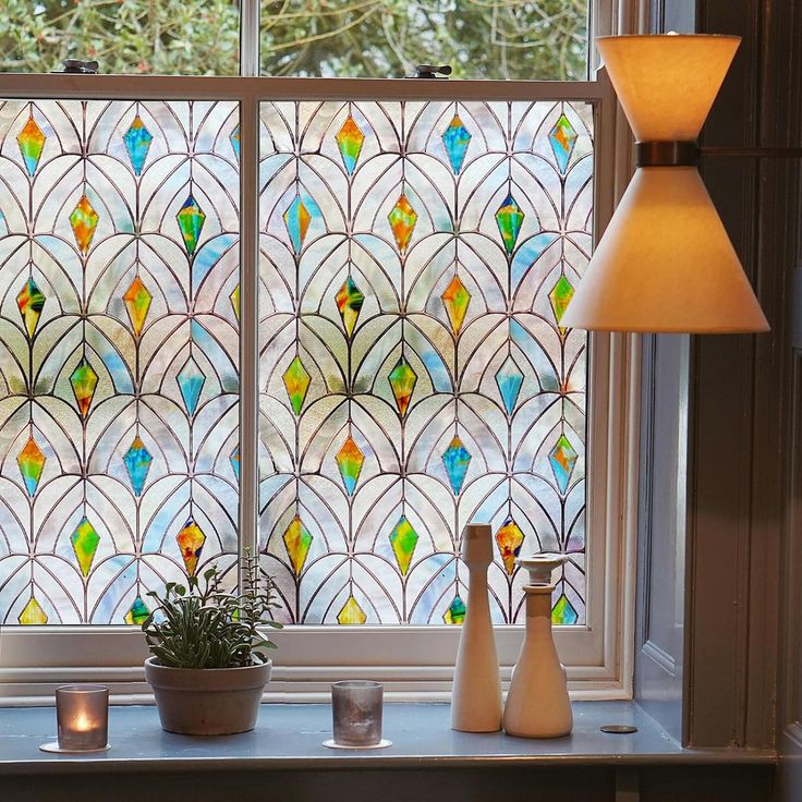 a stained glass window with two vases and a lamp on the table next to it